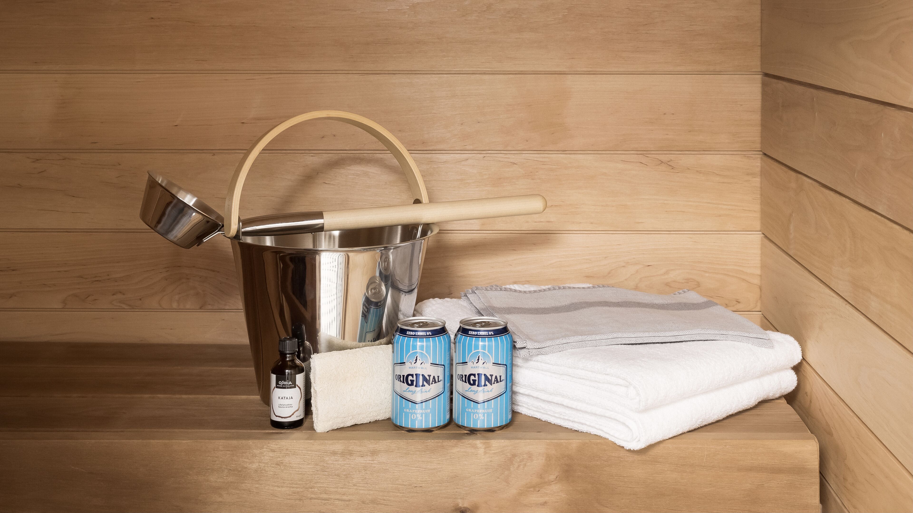 Un banc en bois, un seau en métal, une bouteille et deux canettes de bière.
