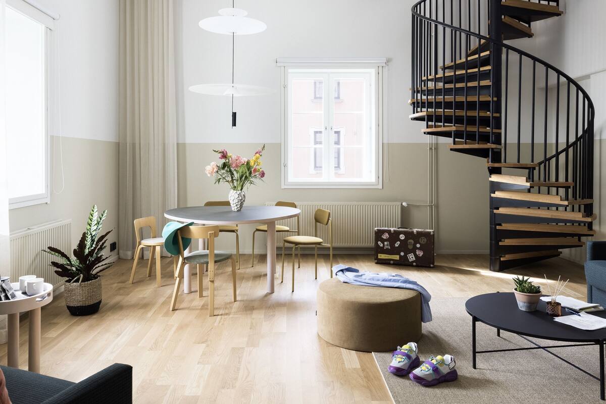 A modern living room with a spiral staircase, a round dining table, and a cozy seating area.