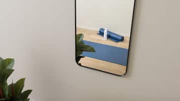 A mirror reflecting a yoga mat and a bottle on a wooden floor.