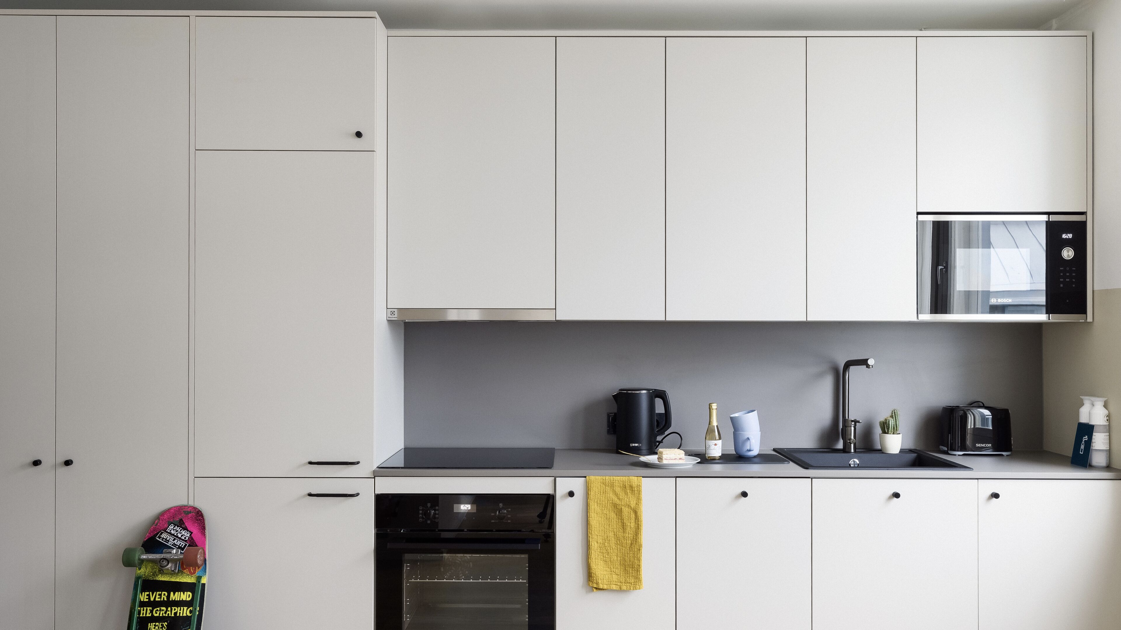 A modern kitchen with white cabinets, a Bosch microwave, a coffee maker, and a dishwasher.