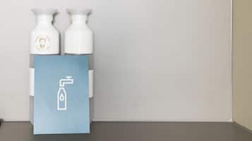 Two white bottles with a logo and text on a blue towel with a faucet icon.