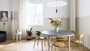 A modern dining area with a round table, four chairs, a vase of flowers, a potted plant, a small side table, and a lamp. - Bob W Helsinki City Centre (Helsinki)