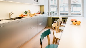 A modern kitchen with a sink, cabinets, and a dining area with chairs and a table.