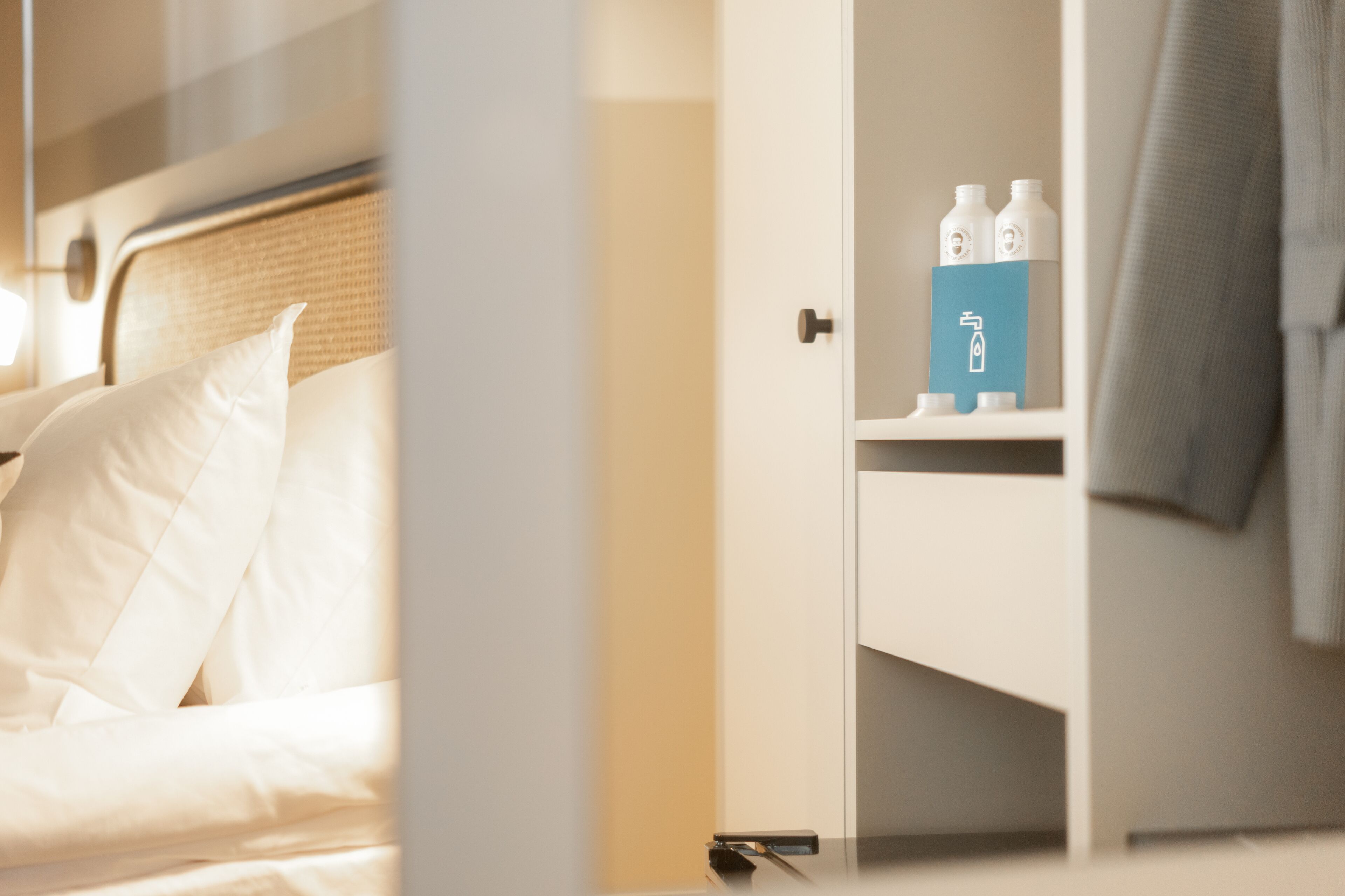 Une chambre d’hôtel avec un lit, une table de chevet et une étagère contenant des articles de toilette.