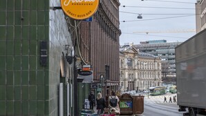 A street with outdoor seating, a craft beer bar sign, and a tram in the background.