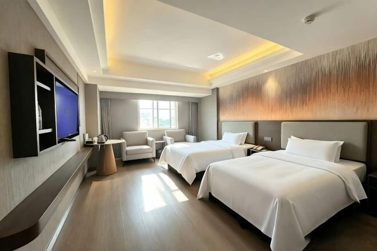Een hotelkamer met twee bedden, een televisie, een bureau en een stoel.