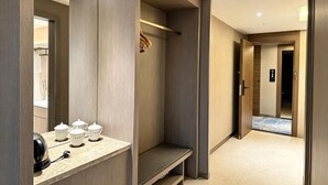 Ein Hotelgang mit einer Bank, einem Kleiderständer und einer Tür zu einem weiteren Zimmer.