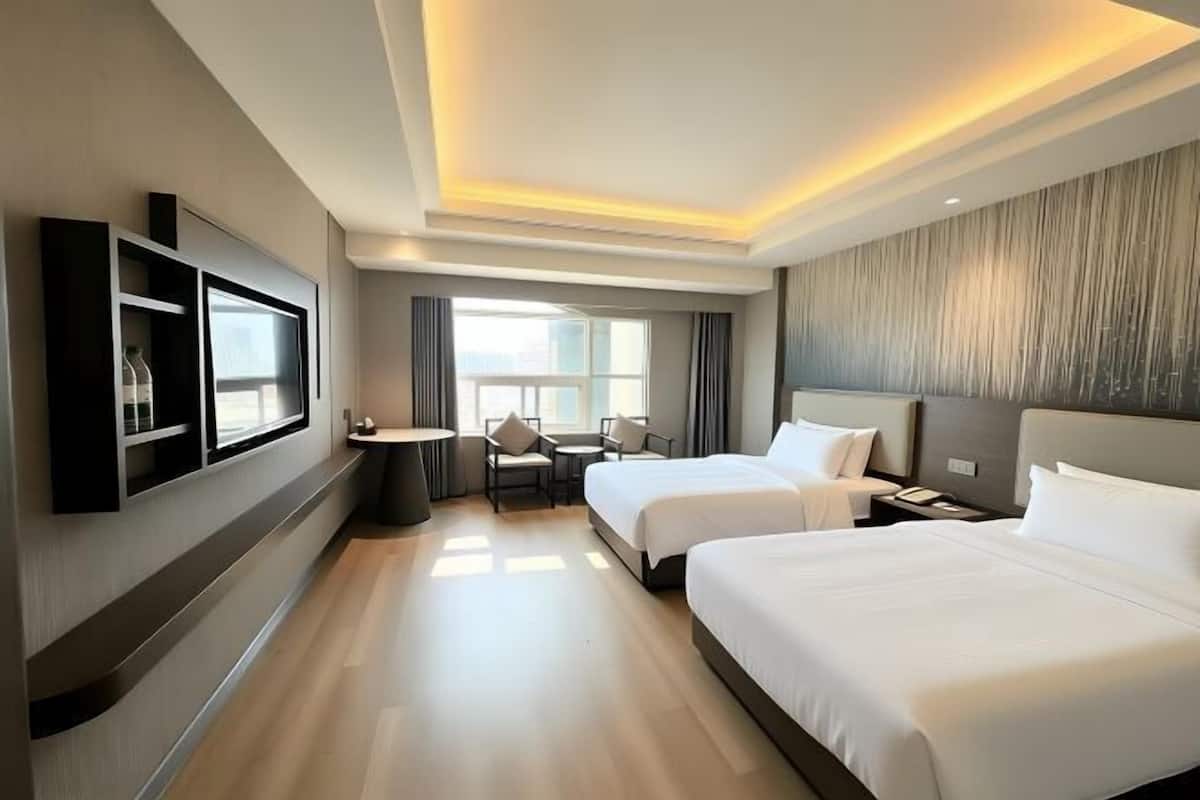 Een hotelkamer met twee bedden, een televisie, een bureau en een stoel.