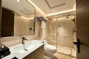 Une salle de bain moderne avec un grand miroir, un lavabo, des toilettes et une douche à parois de verre.