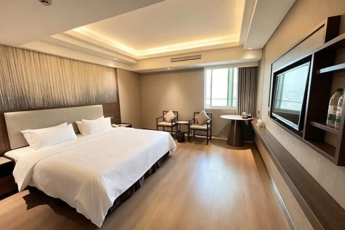 Een hotelkamer met een groot bed, een bureau met stoelen, een kleine tafel en een televisie.