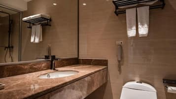 A modern bathroom with a marble sink, a toilet, and a mirror.