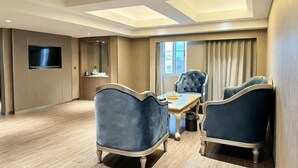 A hotel room with a dining area, a flat-screen TV, a large window, and a ceiling with skylights. - Wanjia Dongfang Hotel (Shishi)
