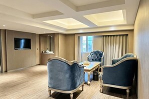 A hotel room with a dining area, a flat-screen TV, a large window, and a ceiling with skylights. - Wanjia Dongfang Hotel (Shishi)