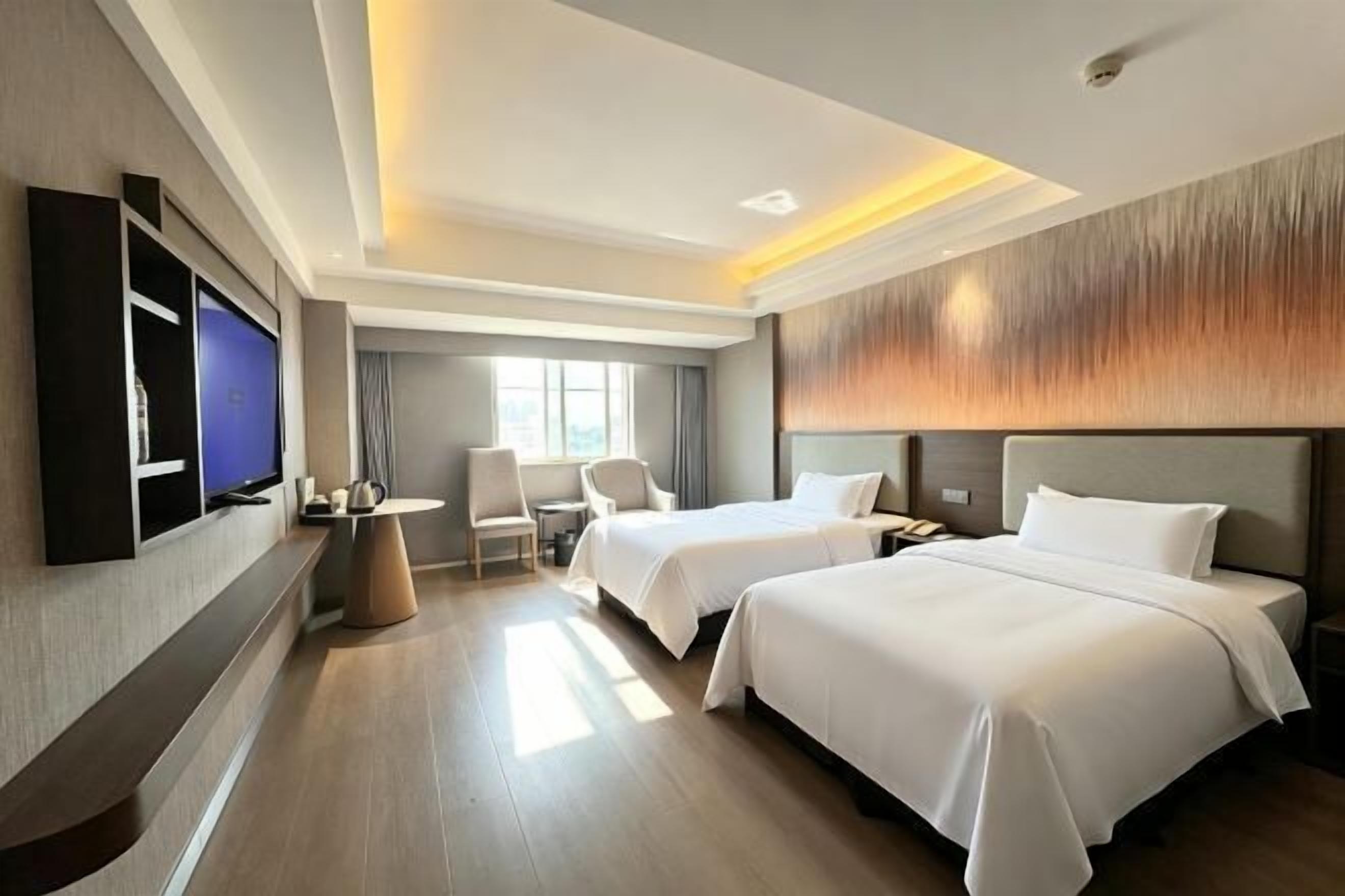 Une chambre d’hôtel avec deux lits, une télévision, un bureau et une chaise.