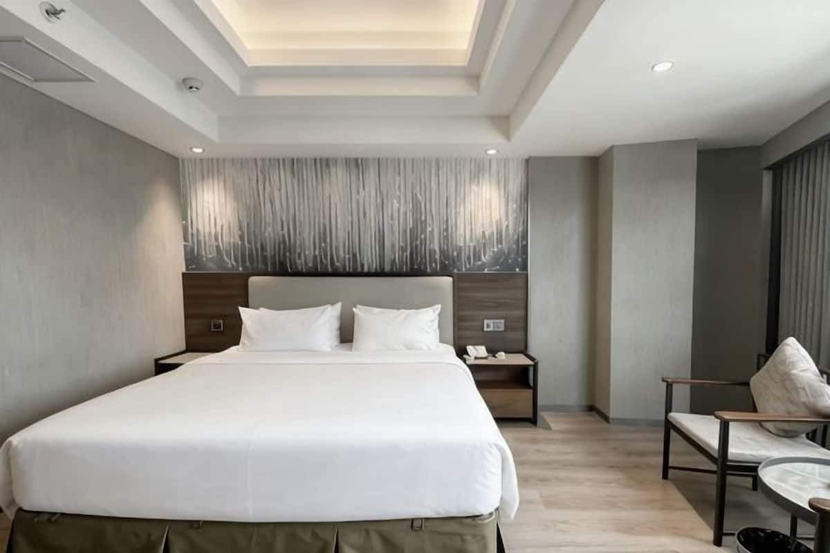 Een moderne hotelkamer met een groot bed, een bureau en een stoel.