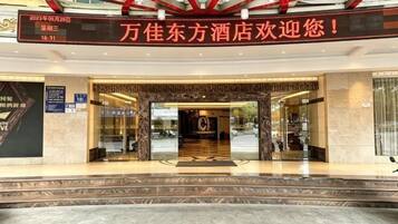 A hotel entrance with a digital sign, glass doors, and a marble floor.