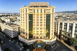 A high-rise hotel with a prominent entrance, multiple floors, and a large glass facade. - Wanjia Dongfang Hotel (Shishi)