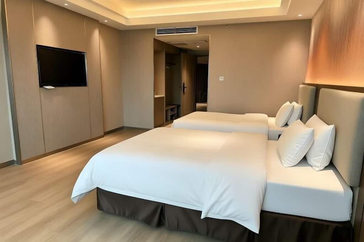 A hotel room with a large bed, a flat-screen TV, and a wooden floor.