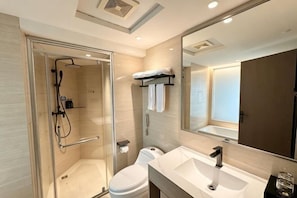 A modern bathroom with a glass-enclosed shower, a white toilet, a sink with a mirror, and a towel rack. - Wanjia Dongfang Hotel (Shishi)