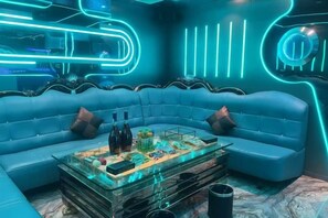 Ein moderner Loungesessel mit einem blauen Sofa, einem Glastisch und Neonbeleuchtung.