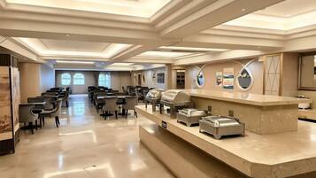 Un amplio vestíbulo de hotel con mostrador de recepción, zona de estar y grandes ventanales.