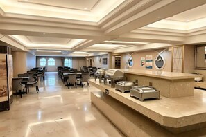 Een ruime hotellobby met een receptiebalie, een zithoek en grote ramen.