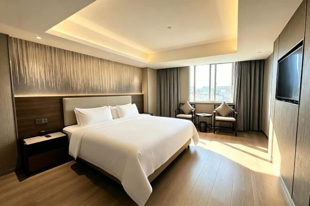 Een moderne hotelkamer met een groot bed, een bureau, een stoel en een televisie.