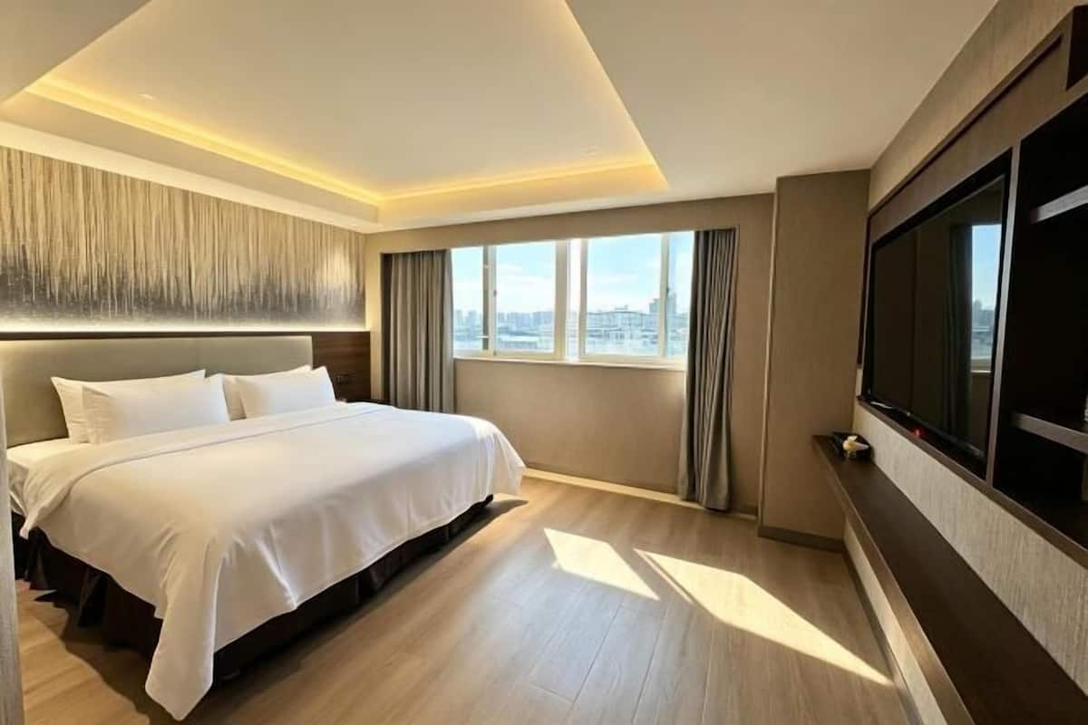 Een hotelkamer met een groot bed, uitzicht over de stad, een televisie en een modern design.