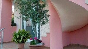A pink building with a curved staircase and potted plants. - 60Quattro Bedrooms (Lamezia Terme)
