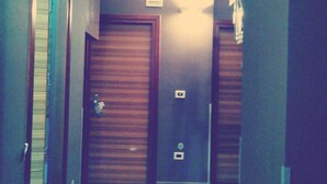 A narrow hallway with wooden doors and a light fixture on the wall. - 60Quattro Bedrooms (Lamezia Terme)