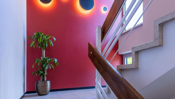 Un interior moderno con una pared roja, una escalera y una planta en maceta.