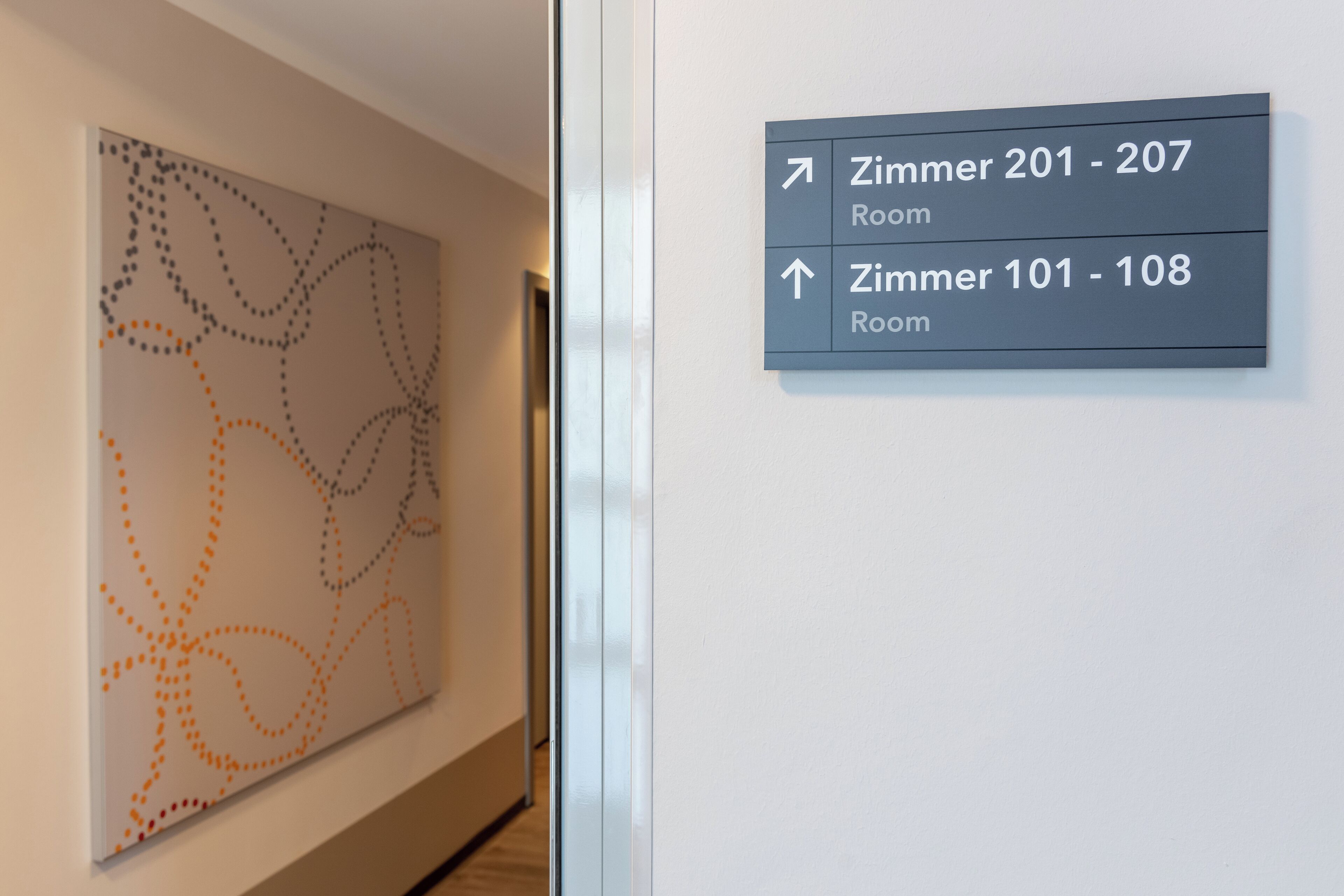 A hallway with directional signs for rooms 201-207 and 101-108.
