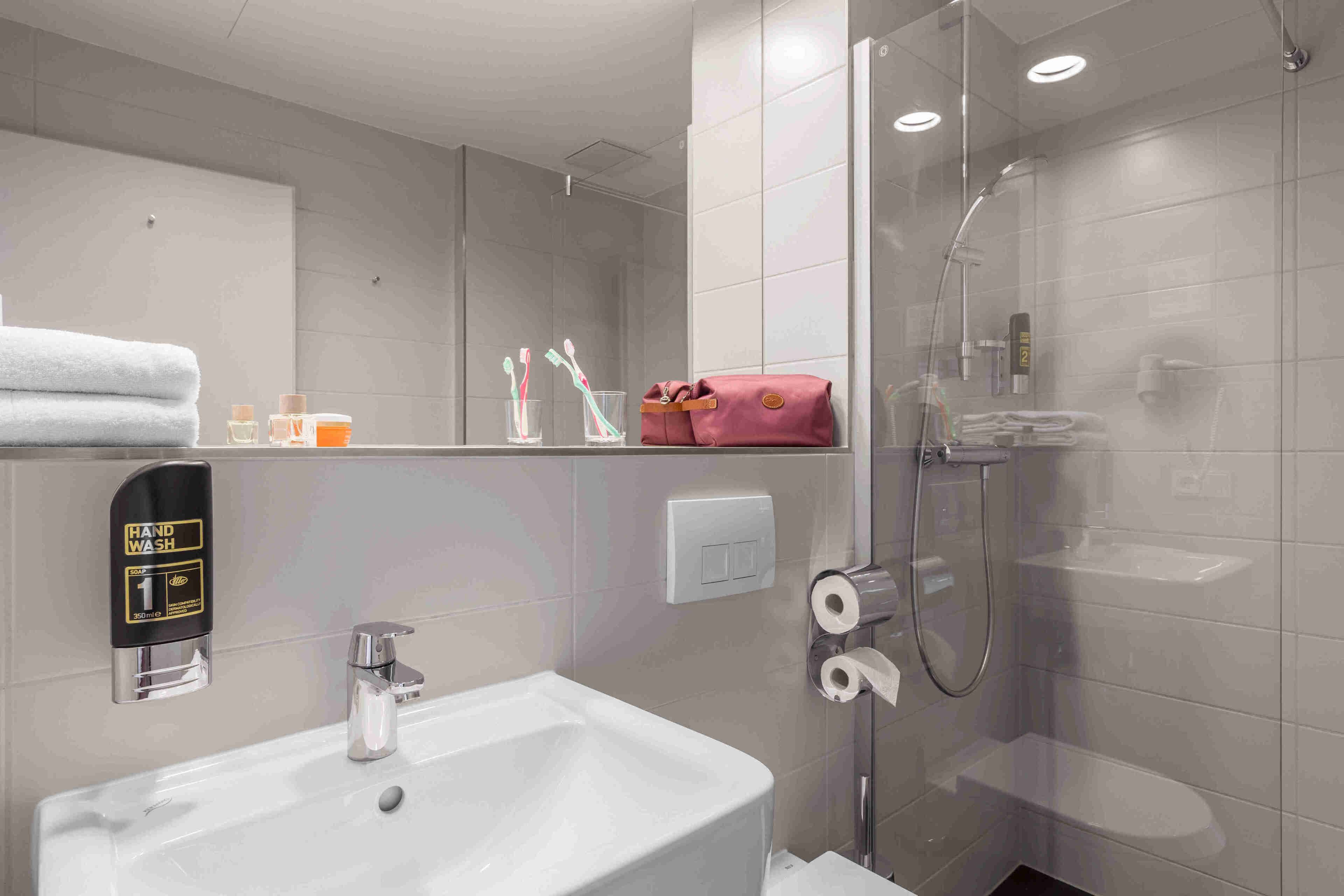 Une salle de bain moderne équipée d’un lavabo, d’un point d’eau et d’une douche à parois de verre.