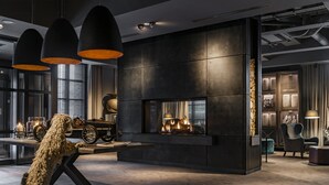 Ein modernes Interieur mit Kamin, Pendelleuchten und einer Vitrine mit Oldtimern.