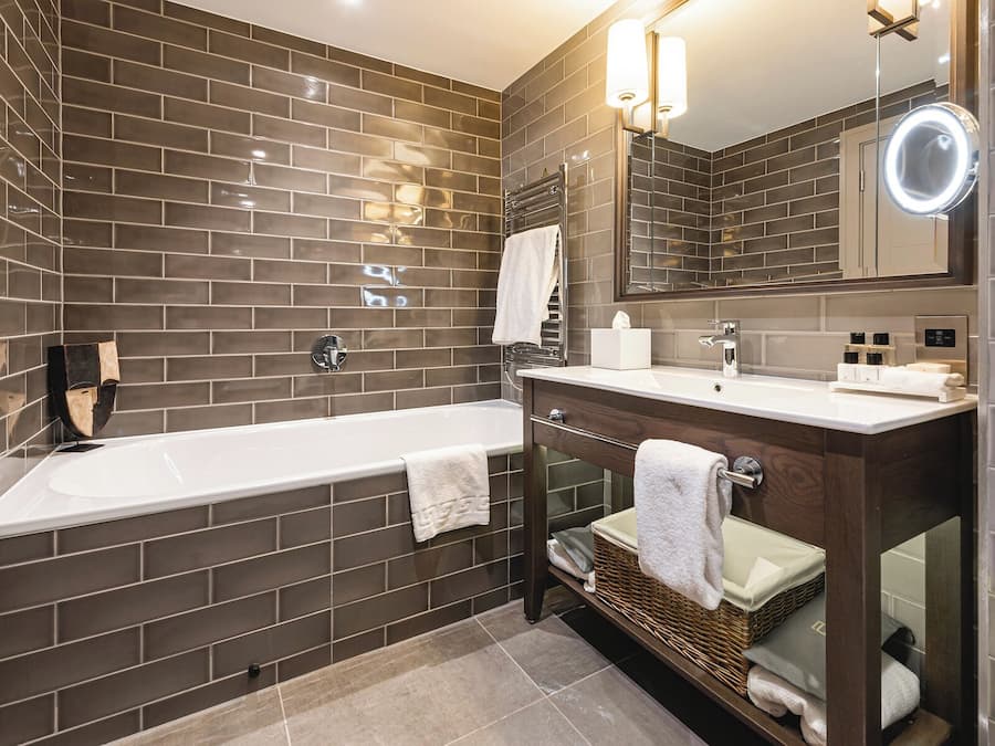 Un baño moderno con una bañera grande, un tocador con espejo y un perchero para toallas.