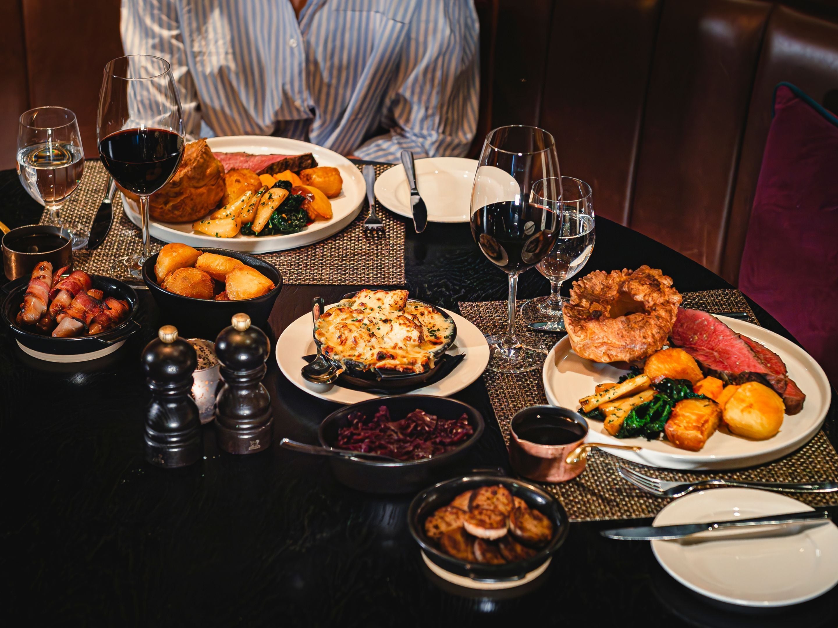 Mesa de comedor lista con platos, copas de vino y cubiertos.
