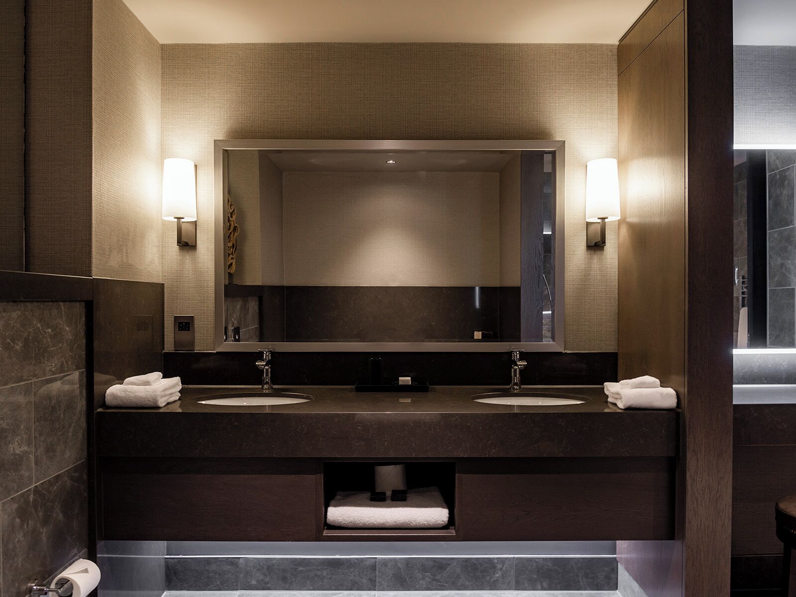 A modern bathroom with a large mirror, two sinks, and a towel rack.