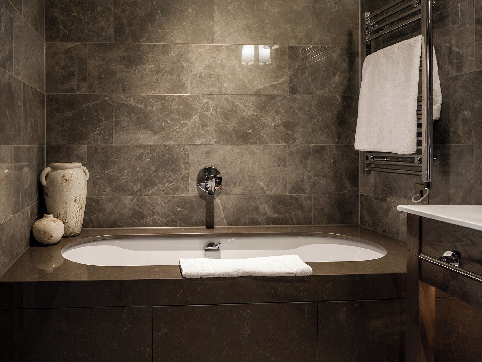 A modern bathroom with a freestanding bathtub, a towel rack, and a vanity with a mirror.
