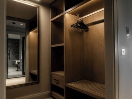A walk-in closet with wooden shelves, a hanging rack, and a mirrored closet door.