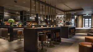 Eine moderne Bar mit hohen Barhocker, einer glänzenden Bar und einer Auswahl an Spirituosen.