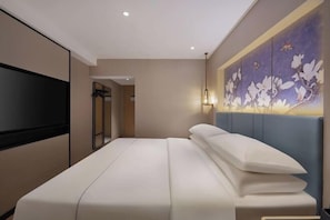 A hotel room with a bed, a TV, a wall-mounted artwork, and a door leading to a bathroom. - Magnotel Hotel (Nanjing Hongshan Zoo Maigaoqiao Subway Station) (Nanjing)