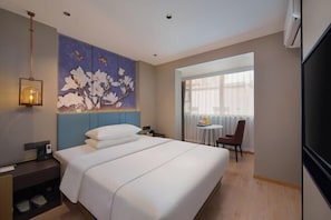 A hotel room with a large bed, a painting on the wall, a desk with a lamp, and a view of the outside through a window. - Magnotel Hotel (Nanjing Hongshan Zoo Maigaoqiao Subway Station) (Nanjing)
