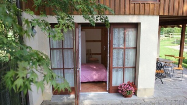 Une chambre avec un lit, un plafond en bois et une vue sur un jardin.