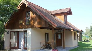 Une maison en bois à deux étages, avec un toit en pente, un porche à l’avant et un petit jardin.