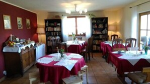 Un espace repas avec plusieurs tables recouvertes de nappes rouges, entourées d’étagères et de chaises.