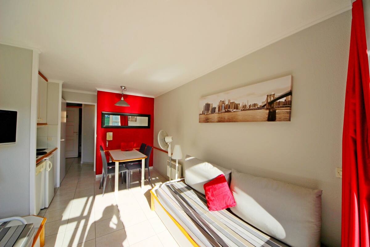 Une chambre d’hôtel de taille réduite comprenant un lit, un coin repas et une kitchenette.