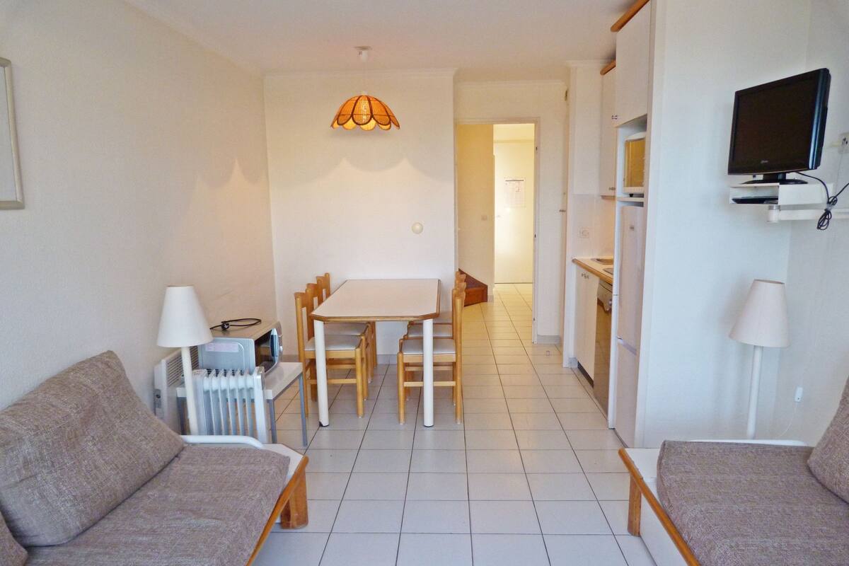 Un espace de vie compact comprenant un coin repas, une kitchenette et un coin salon.