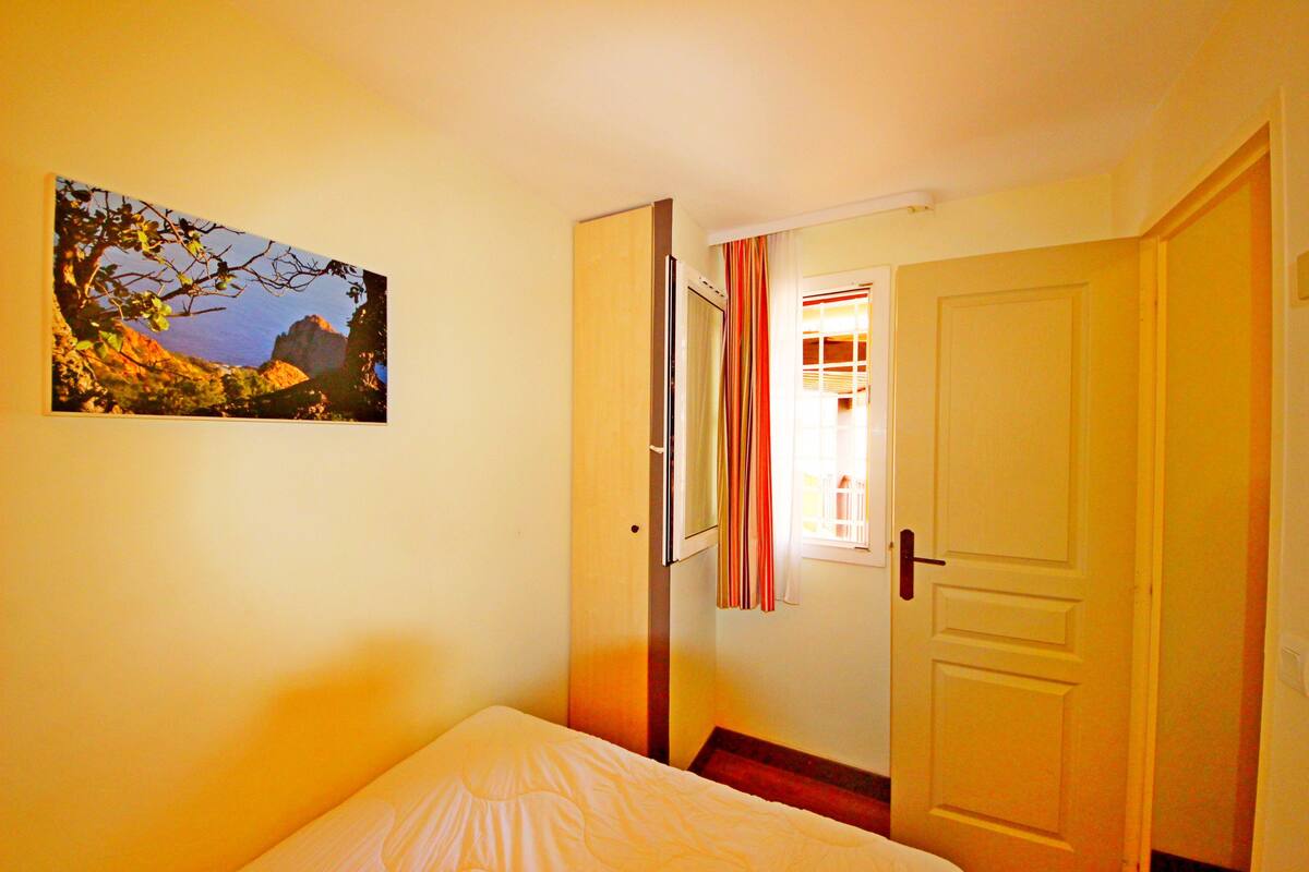 Une chambre à coucher avec un lit, une porte donnant sur une autre pièce et un tableau accroché au mur.