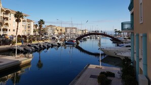 A marina with boats docked, a pedestrian bridge, and buildings with balconies. - La Pierre Verte Camping Village (Fréjus)