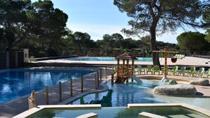 A pool area with multiple swimming pools, a wooden gazebo, and green chairs. - La Pierre Verte Camping Village (Fréjus)